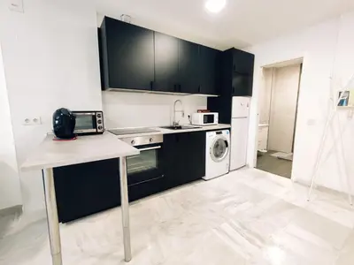 a kitchen with black cabinets and a washer and dryer at Loft Paseo Marítimo in Cádiz