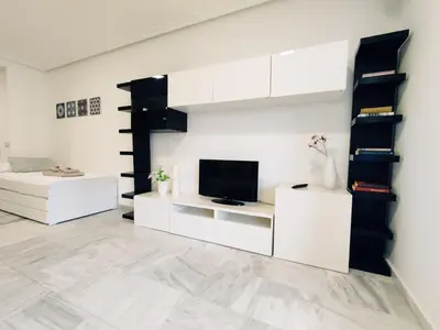 a living room with white furniture and a flat screen tv at Loft Paseo Marítimo in Cádiz