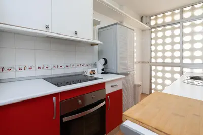 a kitchen with red and white cabinets and a sink at Apartoyou - Fuentebravía Playa in El Puerto de Santa María