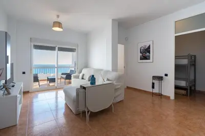a living room with a white couch and a view of the ocean at Apartoyou - Fuentebravía Playa in El Puerto de Santa María