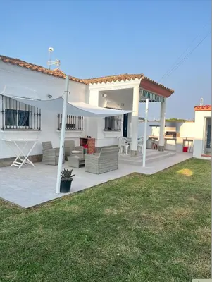 a white house with a patio and a yard at Fantástico chalet con piscina 2 km de la barrosa in Chiclana de la Frontera