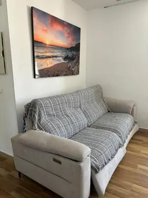 a couch in a living room with a picture on the wall at Fantástico chalet con piscina 2 km de la barrosa in Chiclana de la Frontera