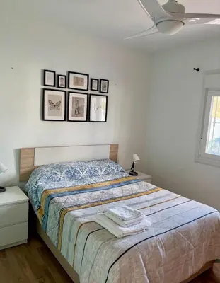 a bedroom with a bed with three pictures on the wall at Fantástico chalet con piscina 2 km de la barrosa in Chiclana de la Frontera