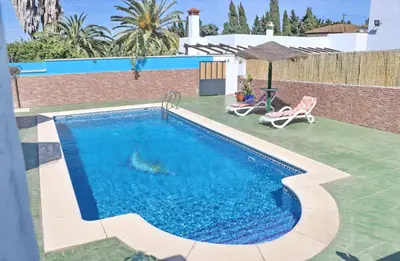 a swimming pool with blue water in a yard at Chalet Blue in Conil de la Frontera