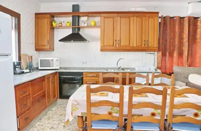 a kitchen with wooden cabinets and a table with chairs at Chalet Blue in Conil de la Frontera