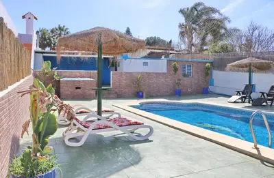 a swimming pool with two chairs and an umbrella at Chalet Blue in Conil de la Frontera