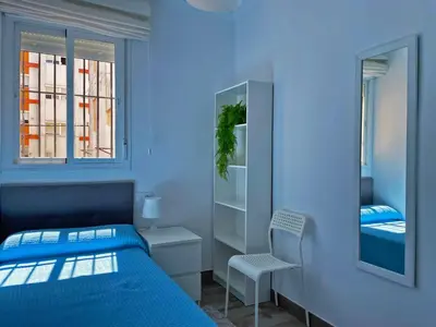 a blue bedroom with a bed and a chair at Apartamento Alván - Ole Solutions in Jerez de la Frontera