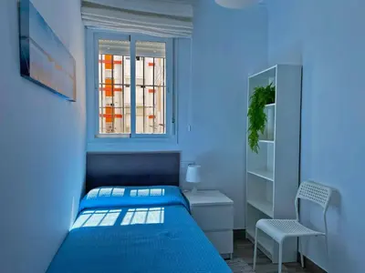 a blue bedroom with a bed and a chair at Apartamento Alván - Ole Solutions in Jerez de la Frontera