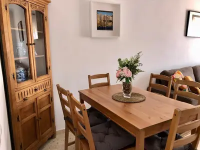 a dining room table with a vase of flowers on it at Sol y playa Sanlúcar in Sanlúcar de Barrameda