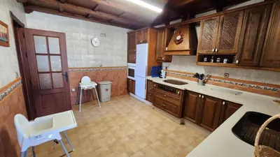 a kitchen with wooden cabinets and a white refrigerator at LOS ALMENDROS in Chiclana de la Frontera