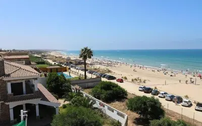 a beach with a lot of people and the ocean at LOS ALMENDROS in Chiclana de la Frontera