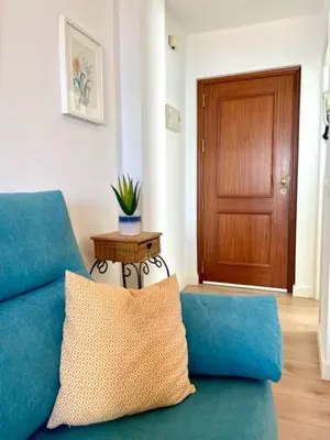a blue couch with a pillow in a living room at GATU PREMIUM Villa Poniente, junto la playa de Valdelagrana 