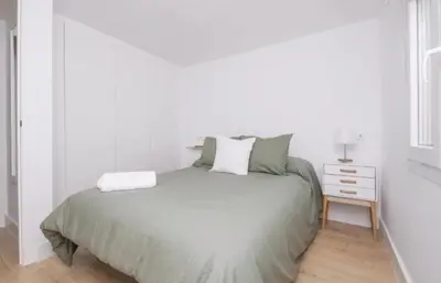 a white bedroom with a bed and a night stand at En el mismo Centro - Aires del Puerto in El Puerto de Santa María