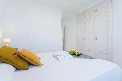 a white bed with yellow pillows and flowers on it at Luminoso 3 rooms 2 Baños Parking in Jerez de la Frontera