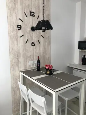 a dining room table with chairs and a clock on the wall at Allo Apartments 
