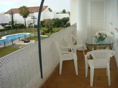a balcony with a table and chairs and a pool at Apartamento residencial de golf y playa Cadiz in Rota