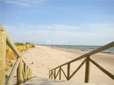 a sandy beach with a wooden fence and the ocean at Apartamento residencial de golf y playa Cadiz in Rota