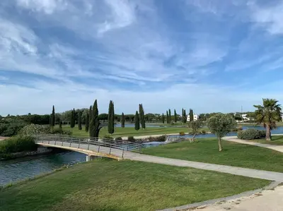 a bridge over a river in a park with trees at Apartamento residencial de golf y playa Cadiz in Rota