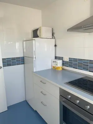 a kitchen with a white refrigerator and a blue floor at Piso coqueto Chiclana in Chiclana de la Frontera