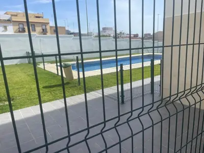 a fence with a view of a swimming pool at Piso coqueto Chiclana in Chiclana de la Frontera
