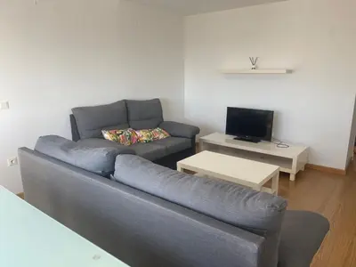 a living room with a couch and a tv at Piso coqueto Chiclana in Chiclana de la Frontera