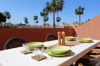 a white table with green plates and glasses on a balcony at Novo Sancti Petri, con piscina todo el año, La Mariposa by Chiclana Dreams in Chiclana de la Frontera