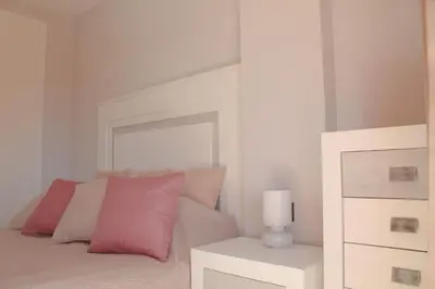 a white bedroom with a bed with pink pillows at Novo Sancti Petri, con piscina todo el año, La Mariposa by Chiclana Dreams in Chiclana de la Frontera