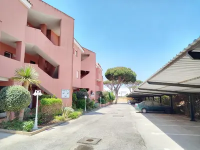 a car parked in a parking lot next to a pink building at Novo Sancti Petri, con piscina todo el año, La Mariposa by Chiclana Dreams in Chiclana de la Frontera