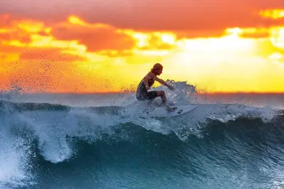 a man riding a wave on a surfboard in the ocean at Novo Sancti Petri, con piscina todo el año, La Mariposa by Chiclana Dreams in Chiclana de la Frontera