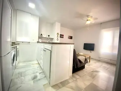 a kitchen with white cabinets and a couch in a room at MyChoice Ático de Luna in Rota