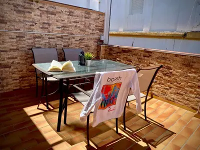 a table and chairs with a book on it at MyChoice Ático de Luna in Rota
