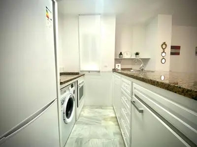 a white kitchen with a refrigerator and a dishwasher at MyChoice Ático de Luna in Rota