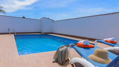 a swimming pool with chairs and a hat next to it at Villanueva - Casa 2 Conil Frontera by Ruralidays in Conil de la Frontera