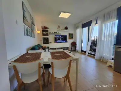 a living room with a table and chairs and a television at Rota Punta Candor Terrace Playa 3 Bajo C in Rota