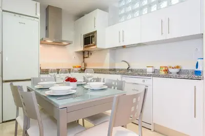 a kitchen with a table and chairs and white cabinets at Apartamento Playa Cádiz by ISA Hoteles in Cádiz