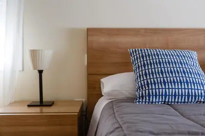 a bed with a blue and white pillow and a lamp at Apartamento Playa Cádiz by ISA Hoteles in Cádiz