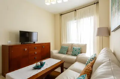 a living room with a couch and a tv at Apartamento Playa Cádiz by ISA Hoteles in Cádiz