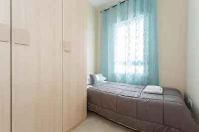a bedroom with a bed and a window with blue curtains at Apartamento Playa Cádiz by ISA Hoteles in Cádiz
