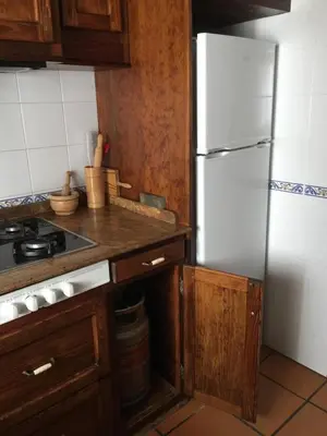 a kitchen with a white refrigerator and wooden cabinets at Relaxing Sanlúcar in Sanlúcar de Barrameda