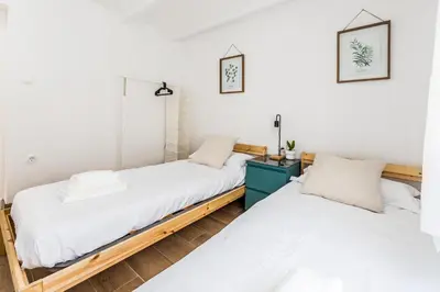 two beds in a room with white walls and wooden floors at Apartamento en CENTRO CIUDAD in El Puerto de Santa María