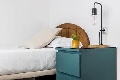 a bed with a blue night stand next to a blue table at Apartamento en CENTRO CIUDAD in El Puerto de Santa María