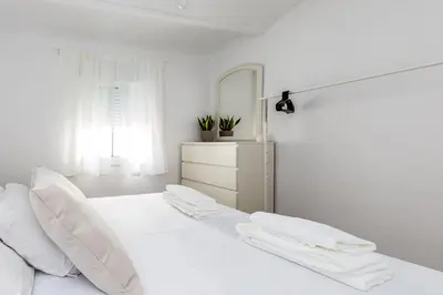 a white bed with white pillows and a mirror at Apartamento en CENTRO CIUDAD in El Puerto de Santa María