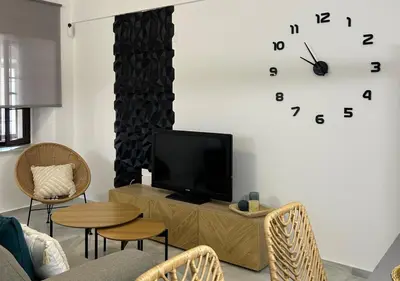 a living room with a tv and a clock on the wall at Apartamento Centro Cabildo Antiguo Convento in Sanlúcar de Barrameda