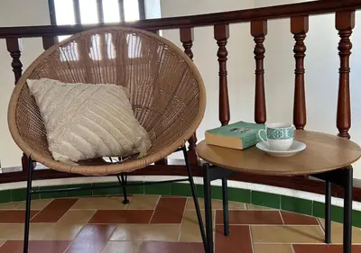 a chair and a table with a cup and a book at Apartamento Centro Cabildo Antiguo Convento in Sanlúcar de Barrameda