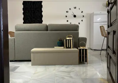a living room with a couch and a clock on the wall at Apartamento Centro Cabildo Antiguo Convento in Sanlúcar de Barrameda
