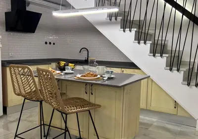a kitchen with a counter with chairs and a staircase at Apartamento Centro Cabildo Antiguo Convento in Sanlúcar de Barrameda