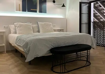 a bedroom with a large bed with a black stool at Apartamento Centro Cabildo Antiguo Convento in Sanlúcar de Barrameda