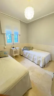 a bedroom with two beds and a chandelier at BAJO EN COSTA GADIR in Chiclana de la Frontera