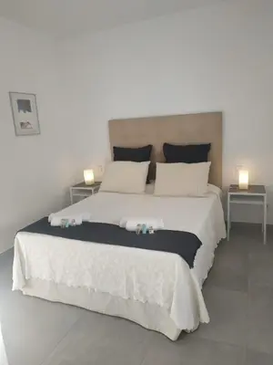 a bedroom with a large white bed with two tables at CHALET ARRILUCE Plaza de parking gratis en la playa in Chiclana de la Frontera