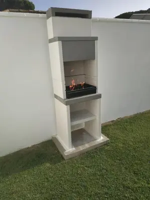 a fireplace in the side of a white wall withgrass at CHALET ARRILUCE Plaza de parking gratis en la playa in Chiclana de la Frontera
